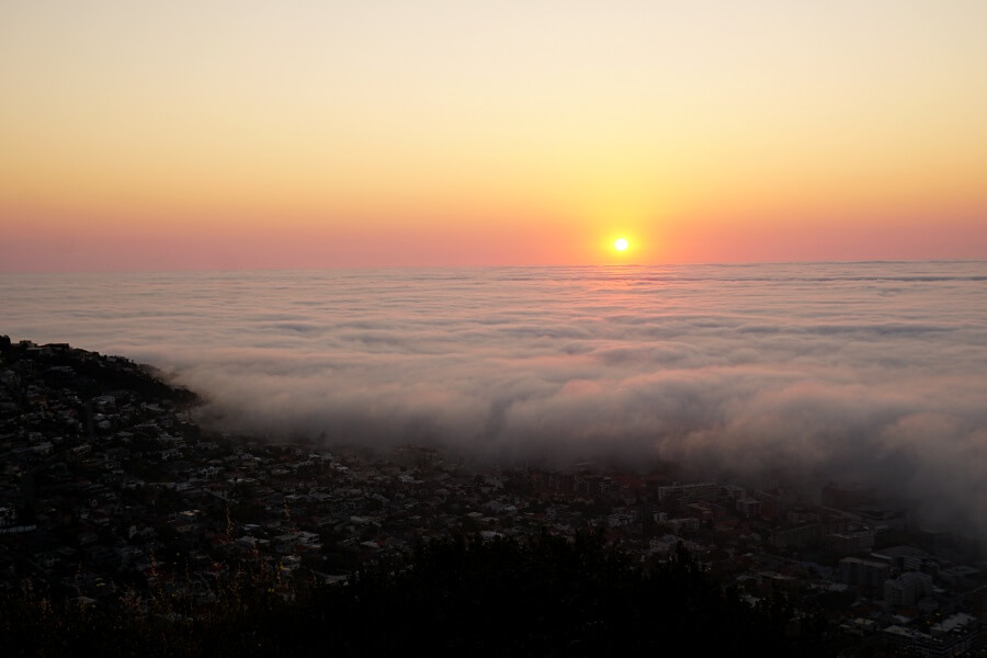 Die Sonne versinkt in einem aufziehenden Meer an Wolken am Signal Hill in Kapstadt
